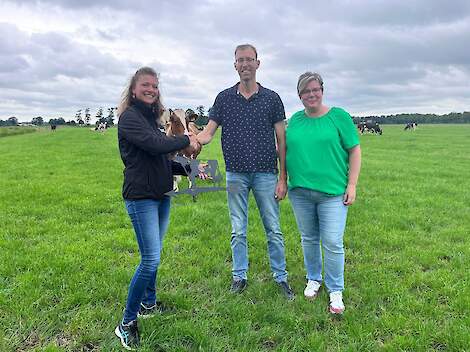 Rundveespecialiste Aliena van der Hout overhandigt de eerste windwijzer aan Gerard en Alien Ketelaar. Binnenkort kunnen ze het gepersonaliseerde bedrijfsbord in ontvangst nemen.