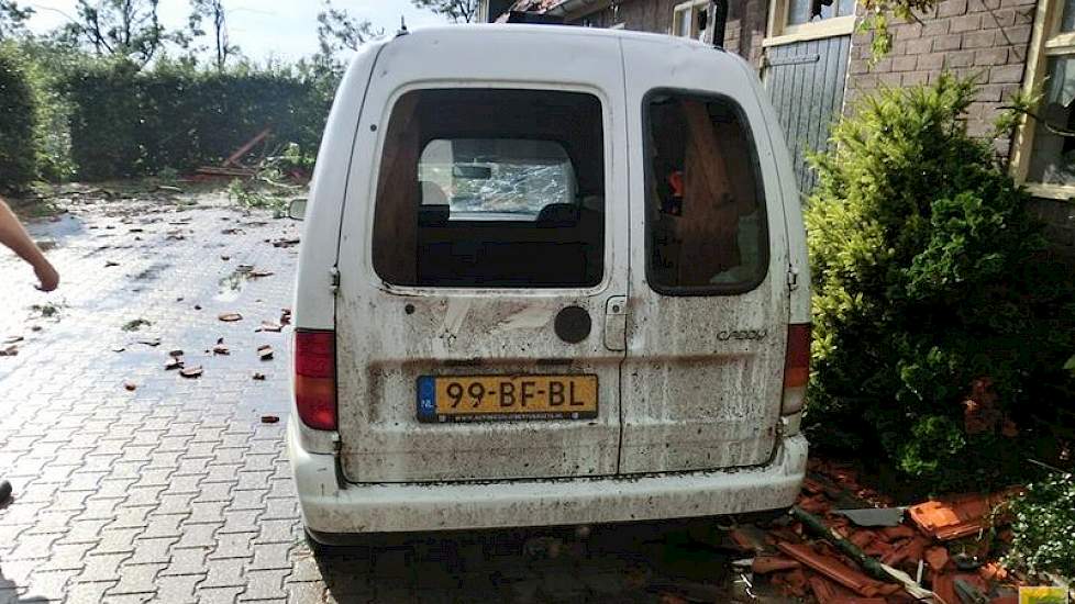 De ramen van de auto werden getroffen door de dakpannen. Ook zit hij vol deuken.