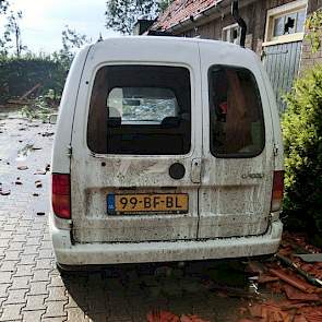 De ramen van de auto werden getroffen door de dakpannen. Ook zit hij vol deuken.