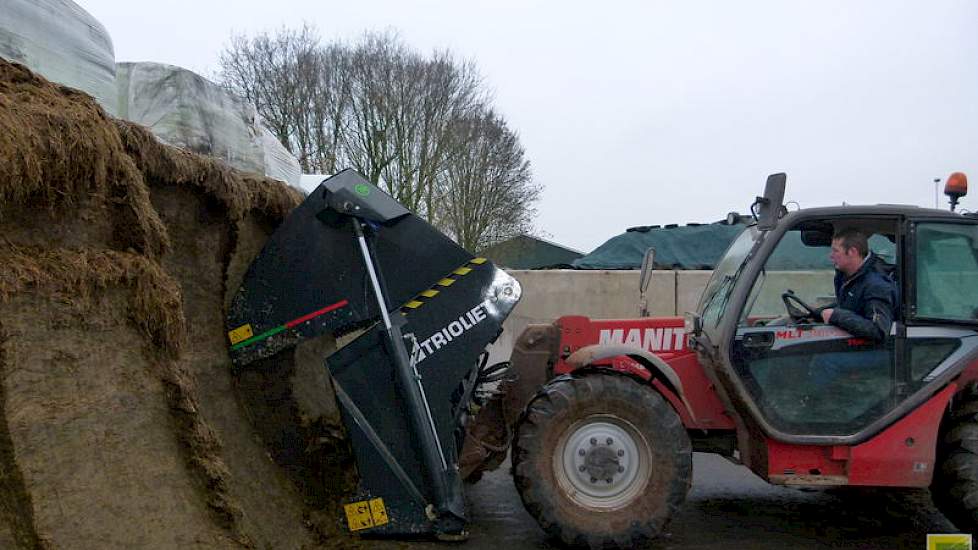 De veehouder vertelt dat hij net een nieuwe kuilhapper van Trioliet heeft gekocht. „Eerder laadde ik de mengwagen met een ‘pelikaanbak’ zonder messen.” Hij demonstreert de nieuwe kuilhapper bij de graskuil. Deze hapt in één keer een hele laag van boven na