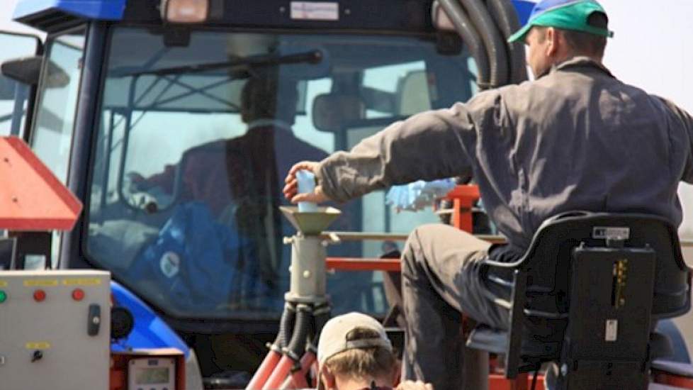 Een medewerker leegt voor elk veldje een zakje zaad in de machine, waar 3 compartimenten boven elkaar zitten